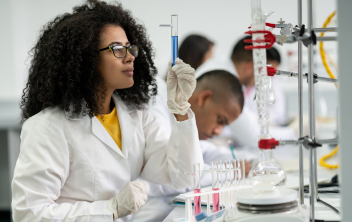 University student in a lab inspecting liquid in a test tube.